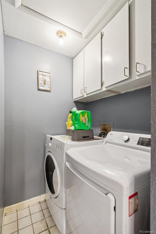 laundry area featuring cabinets, washing machine and clothes dryer, and light tile patterned flooring