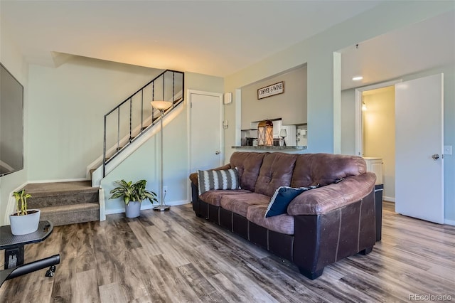 living room featuring stairway, baseboards, and wood finished floors