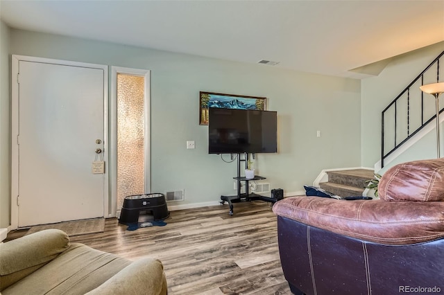 living room with baseboards, stairs, visible vents, and wood finished floors