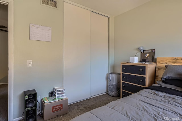 bedroom with a closet, visible vents, and dark carpet