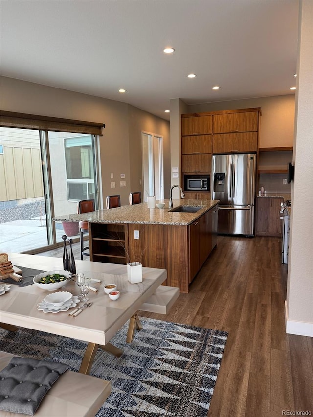 9715 Taylor River Cir, Littleton, CO 80125 - kitchen featuring appliances with stainless steel finishes, brown cabinets, dark wood-style flooring, recessed lighting, and light stone counters