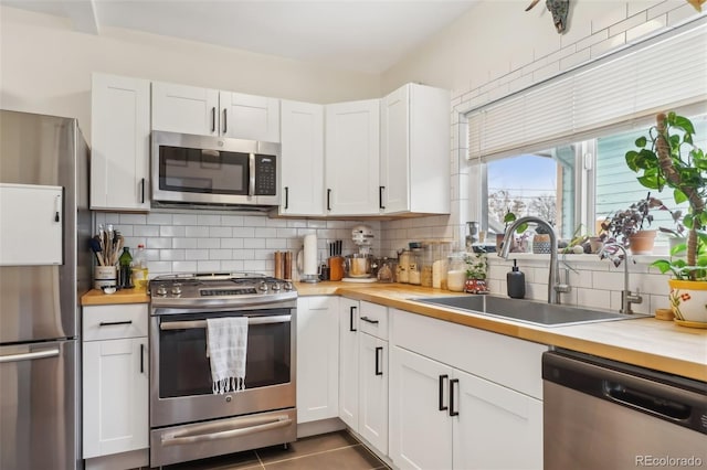 kitchen featuring appliances with stainless steel finishes, wooden counters, white cabinets, and sink