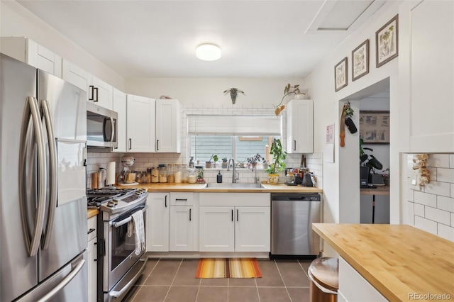 kitchen featuring white cabinets, appliances with stainless steel finishes, wood counters, and sink