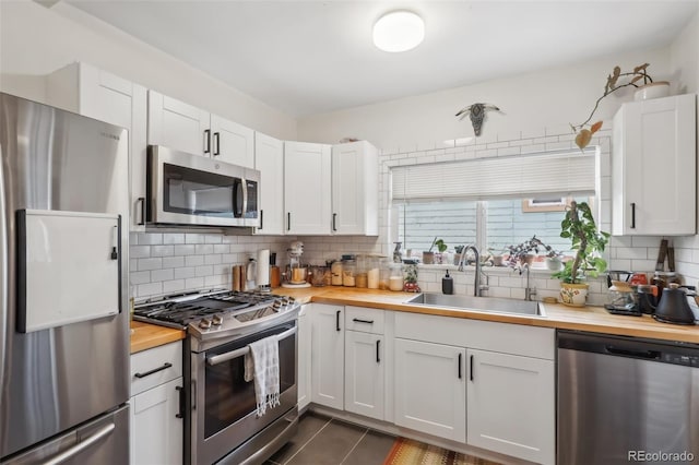 kitchen with white cabinetry, appliances with stainless steel finishes, butcher block countertops, and sink