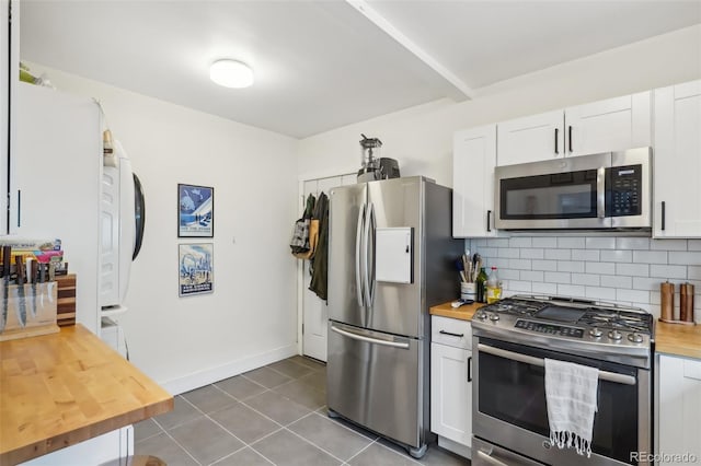 kitchen featuring white cabinets, stainless steel appliances, decorative backsplash, and butcher block counters