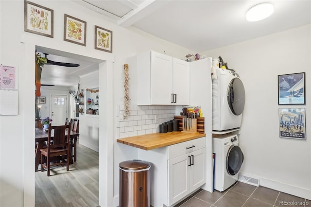 laundry room featuring dark tile patterned flooring and stacked washer / dryer