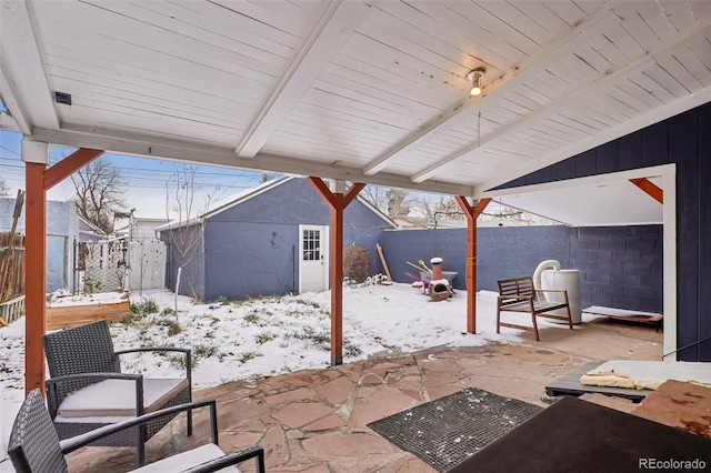 snow covered patio with a storage shed