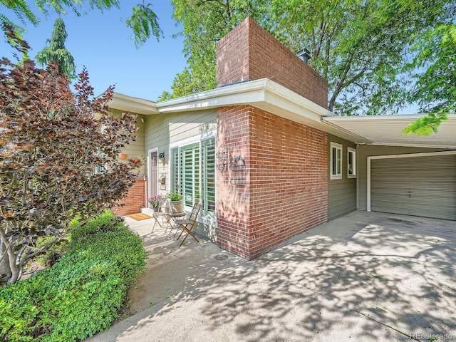 2609 S Dahlia St, Denver, CO 80222 - view of side of home featuring a chimney, concrete driveway, brick siding, and a garage