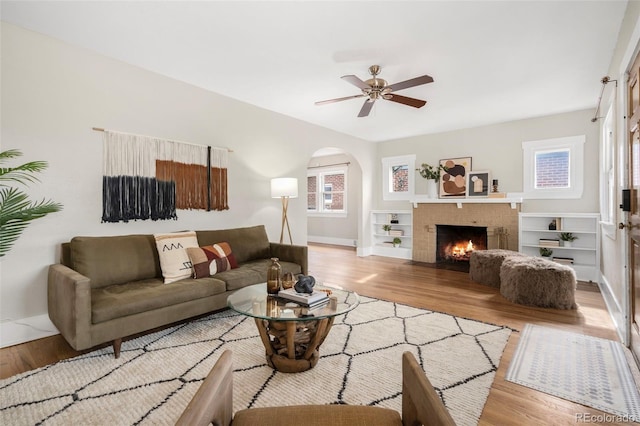 living room with a fireplace, light hardwood / wood-style floors, and ceiling fan