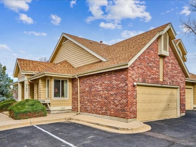 view of front of home featuring brick siding, a garage, and roof with shingles