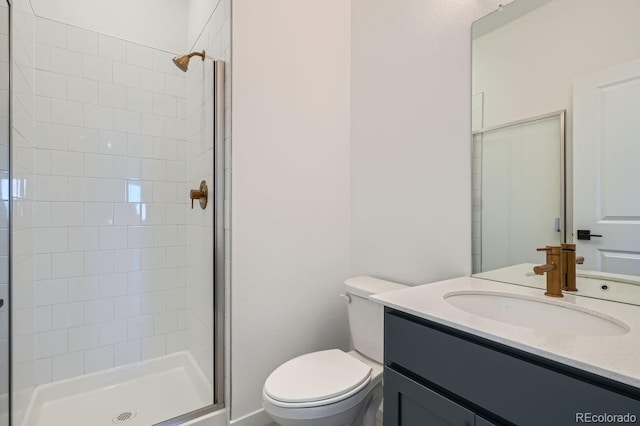 bathroom with tiled shower, vanity, and toilet