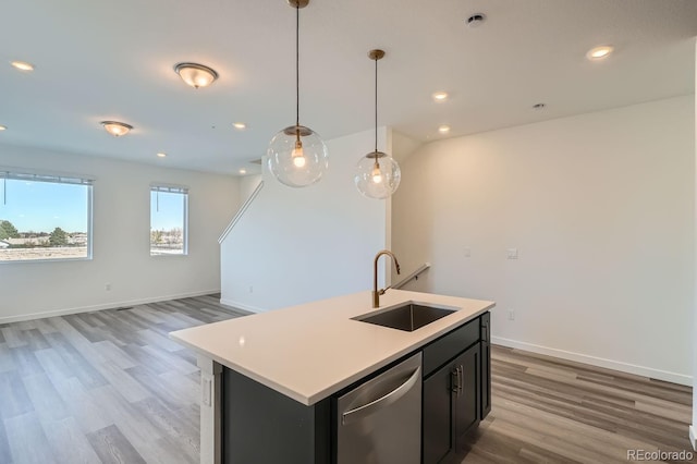 kitchen with dishwasher, sink, light wood-type flooring, an island with sink, and decorative light fixtures