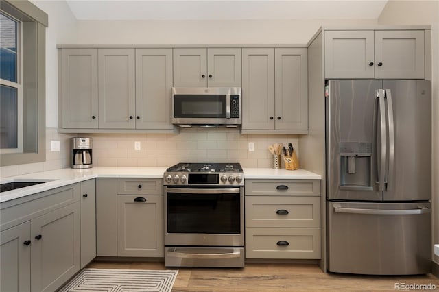 kitchen featuring appliances with stainless steel finishes, gray cabinetry, tasteful backsplash, and light countertops