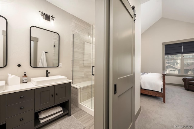 full bathroom with connected bathroom, a stall shower, vanity, lofted ceiling, and baseboards