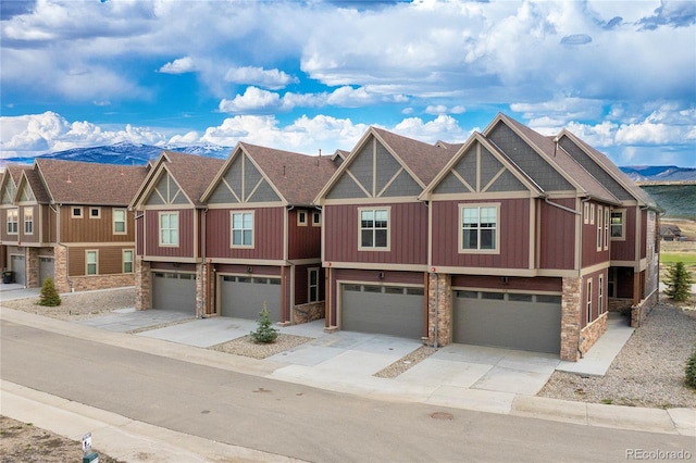 view of property featuring an attached garage, stone siding, and driveway