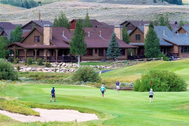 view of property's community with view of golf course, a lawn, and a mountain view