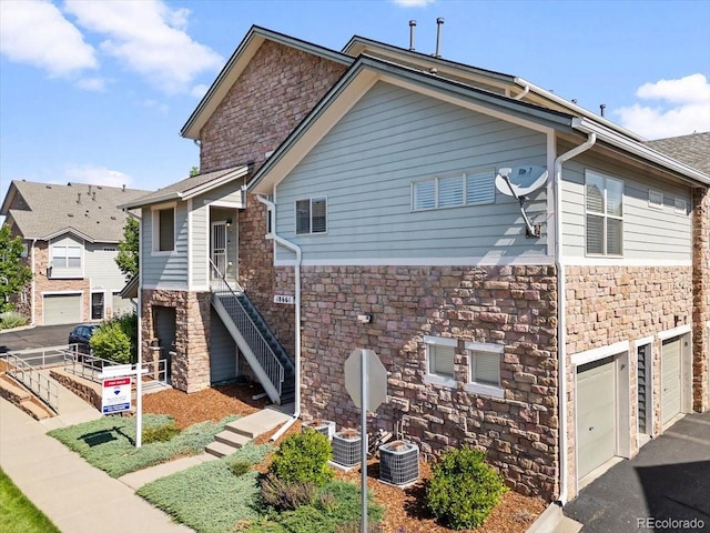 18661 E Water Dr Unit F, Aurora, CO 80013 - view of front of property featuring stone siding, stairway, an attached garage, and asphalt driveway