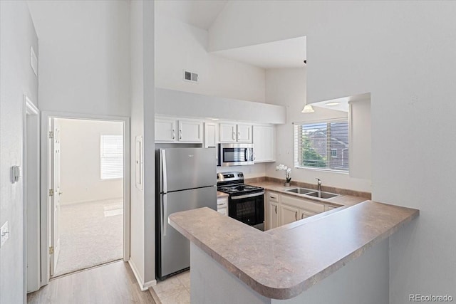 18661 E Water Dr Unit F, Aurora, CO 80013 - kitchen with appliances with stainless steel finishes, high vaulted ceiling, a peninsula, white cabinets, and light wood-style flooring