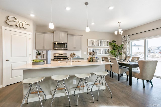 kitchen featuring sink, gray cabinetry, a center island with sink, pendant lighting, and stainless steel appliances