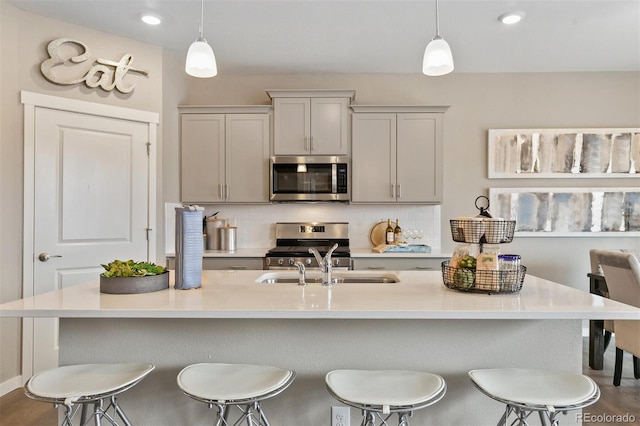 kitchen featuring tasteful backsplash, appliances with stainless steel finishes, hanging light fixtures, and gray cabinetry