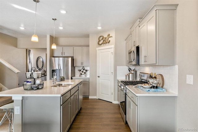 kitchen featuring pendant lighting, sink, a breakfast bar area, appliances with stainless steel finishes, and an island with sink