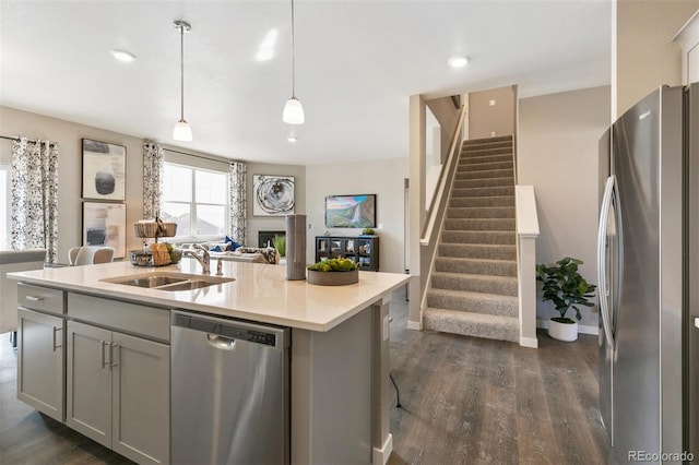 kitchen with sink, gray cabinetry, hanging light fixtures, appliances with stainless steel finishes, and an island with sink