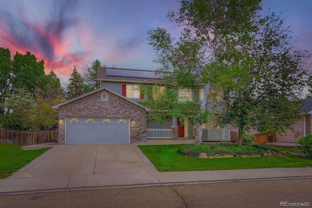 1616 Cedarwood Dr, Longmont, CO 80504 - view of front of house with stone siding, driveway, solar panels, a garage, and covered porch