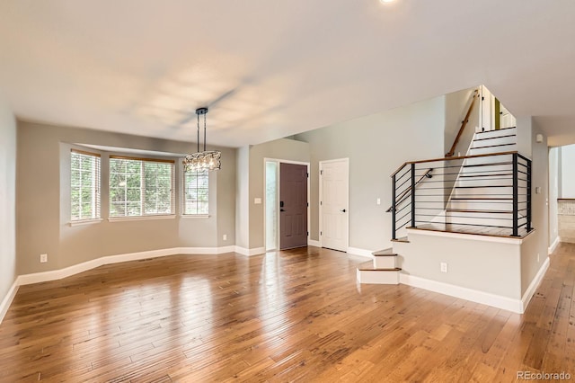 1616 Cedarwood Dr, Longmont, CO 80504 - unfurnished living room featuring stairway, a chandelier, and wood-type flooring