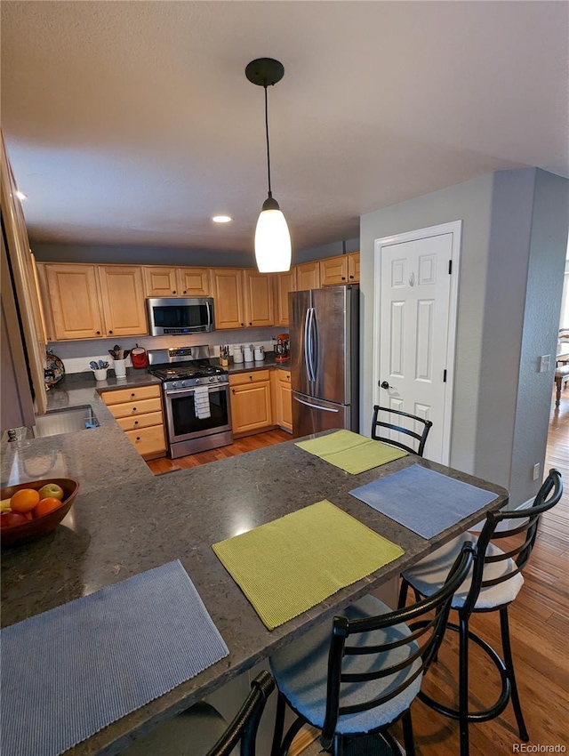 1616 Cedarwood Dr, Longmont, CO 80504 - kitchen with stainless steel appliances, dark countertops, wood finished floors, hanging light fixtures, and recessed lighting