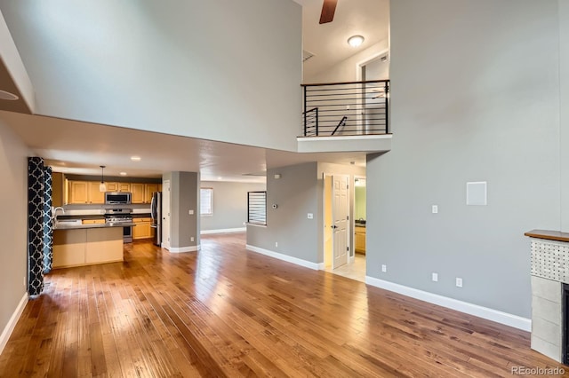 1616 Cedarwood Dr, Longmont, CO 80504 - unfurnished living room featuring light wood-style floors, a high ceiling, a ceiling fan, and recessed lighting