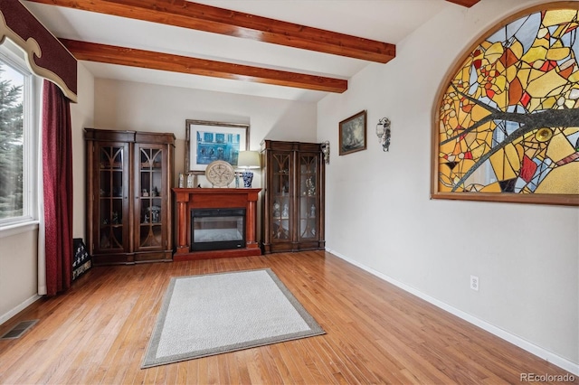 unfurnished living room featuring beam ceiling and light wood-type flooring