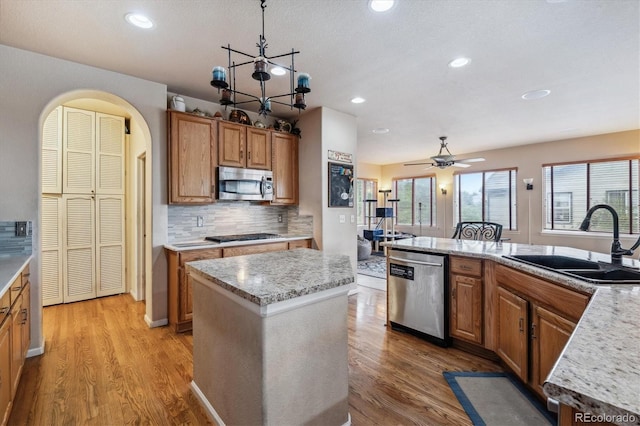 kitchen featuring appliances with stainless steel finishes, light wood-type flooring, sink, tasteful backsplash, and a center island