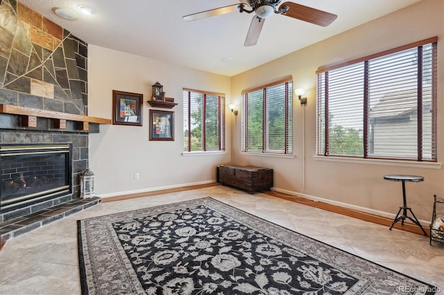 living room with ceiling fan, light tile patterned flooring, and a stone fireplace