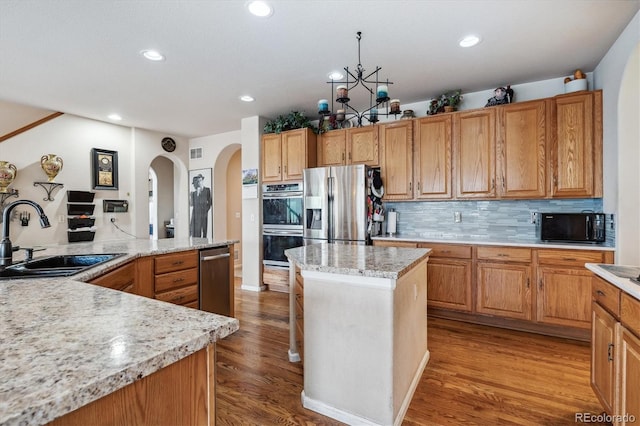 kitchen with stainless steel appliances, wood-type flooring, a center island, and decorative backsplash