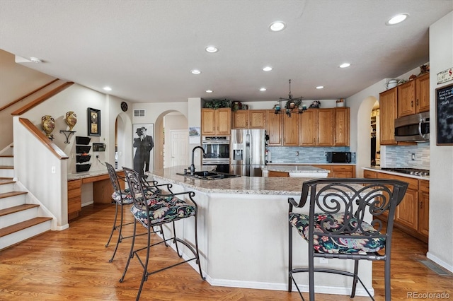 kitchen featuring appliances with stainless steel finishes, sink, light wood-type flooring, and a large island