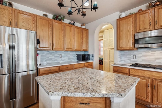 kitchen featuring light stone counters, a chandelier, black appliances, backsplash, and a kitchen island