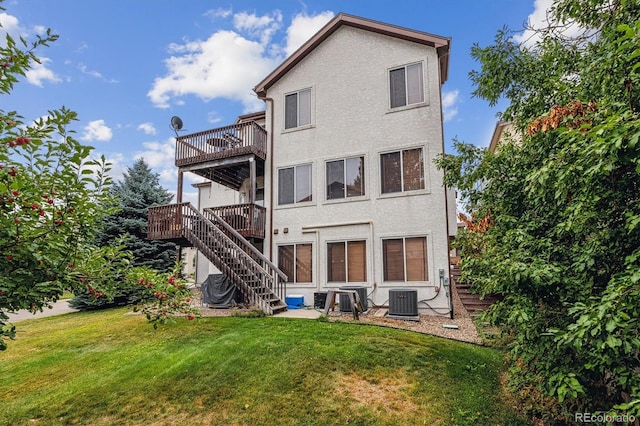 rear view of house featuring central air condition unit, a lawn, and a balcony