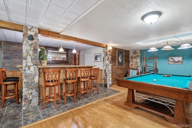 rec room with pool table, bar area, hardwood / wood-style floors, and a textured ceiling