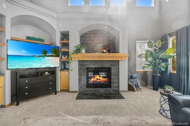 living area with light carpet, a high ceiling, a tiled fireplace, and built in features