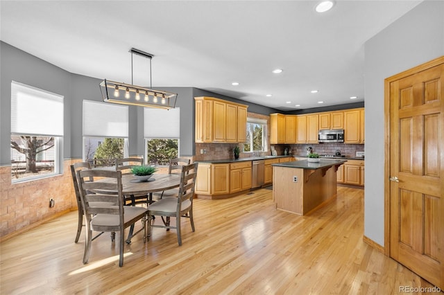 kitchen featuring dark countertops, light wood-style flooring, a breakfast bar, a center island, and stainless steel appliances