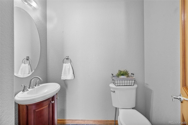 bathroom with toilet, vanity, and baseboards