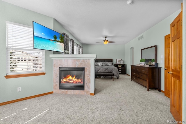 bedroom with arched walkways, carpet floors, a tiled fireplace, and visible vents