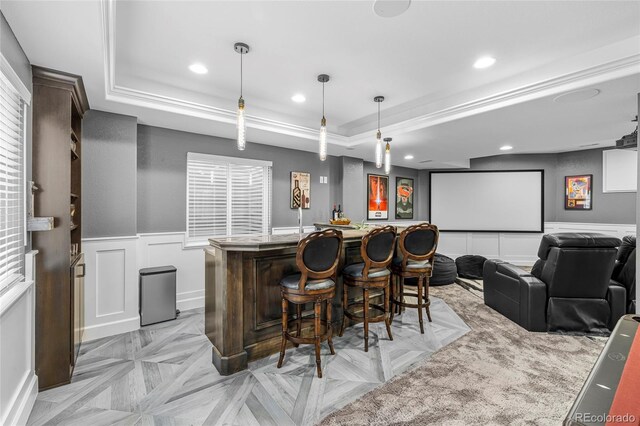 bar featuring a tray ceiling, recessed lighting, hanging light fixtures, wainscoting, and bar