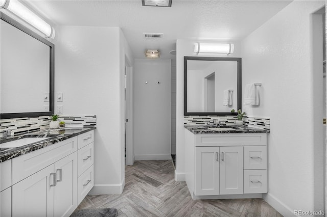 bathroom with tasteful backsplash, visible vents, two vanities, and a sink