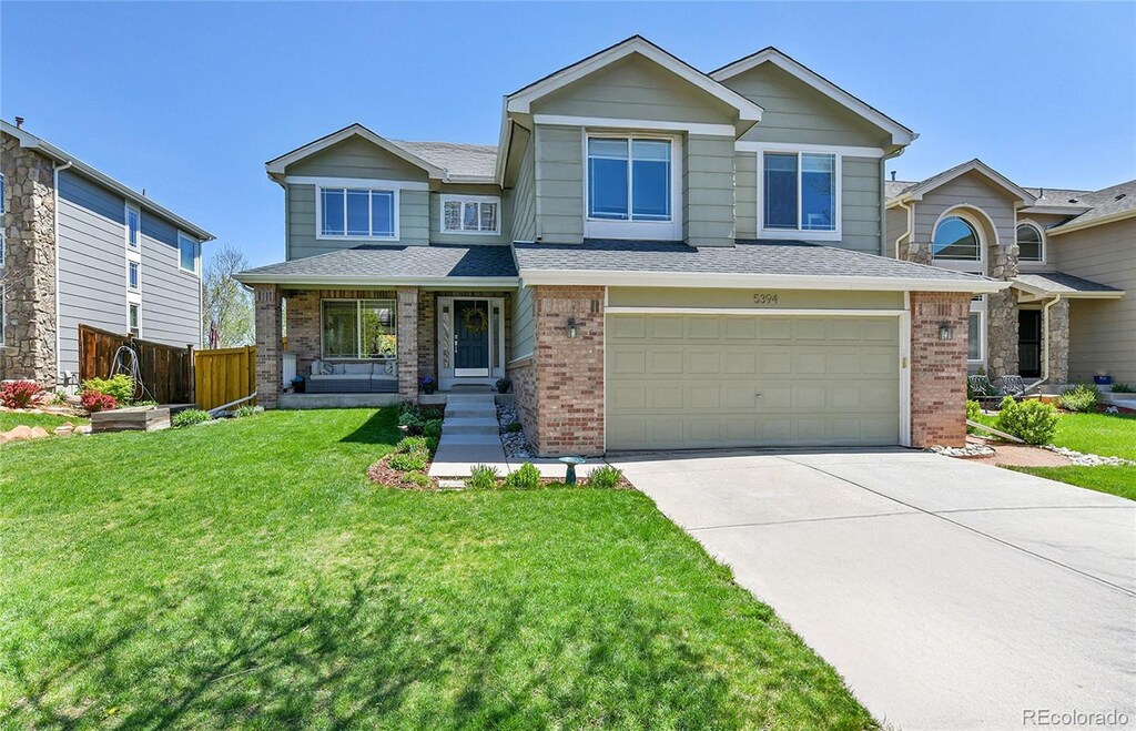 5394 S Gray St, Littleton, CO 80123 - craftsman inspired home featuring a front lawn, fence, brick siding, concrete driveway, and an attached garage