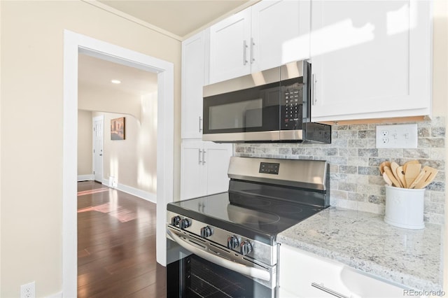 kitchen with white cabinets, stainless steel appliances, light stone countertops, and dark wood-type flooring