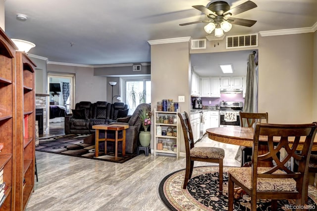 dining area with crown molding, ceiling fan, visible vents, and light wood-style flooring