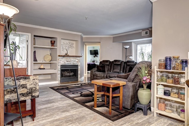living room with built in features, ornamental molding, wood finished floors, and visible vents