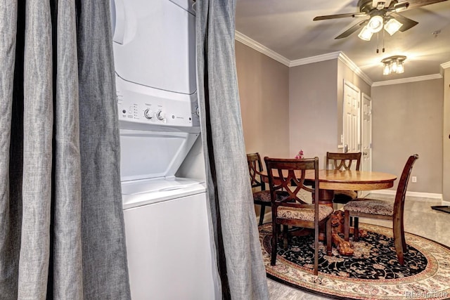 dining area with a ceiling fan, baseboards, stacked washing maching and dryer, and ornamental molding