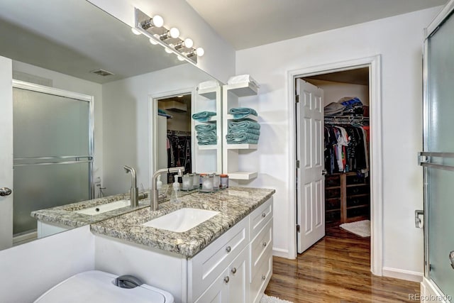 full bathroom with vanity, an enclosed shower, wood finished floors, and a spacious closet